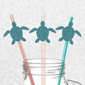 May include: Three teal blue glitter turtle straw toppers on brown and clear straws. The straws are in a clear glass jar with a metal lid and handle. The background is a white glitter surface.