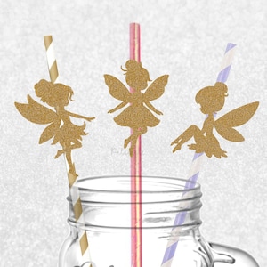 May include: Three paper straws with gold glitter fairy cutouts. One straw has gold stripes, one has pink stripes, and one has purple stripes. The straws are placed in a clear glass jar. The text www.pelemele.etsy.com and Made in the UK appear.
