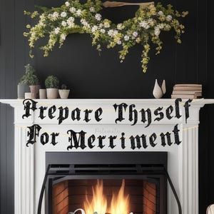 May include: A fireplace with a banner that reads "Prepare Thyself For Merriment." The banner is black with white lettering. The fireplace has a white mantel and a black firebox with a fire burning inside. A floral arrangement hangs above the mantel.