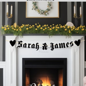 May include: Black and white banner with the text "Sarah & James" in a gothic font. The banner is decorated with black hearts and is hanging above a fireplace.