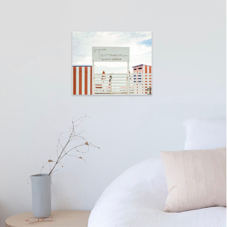 May include: A white wooden gate with a red and white striped wall on either side. A sign above the gate reads "Terrazza Bar Marina".
