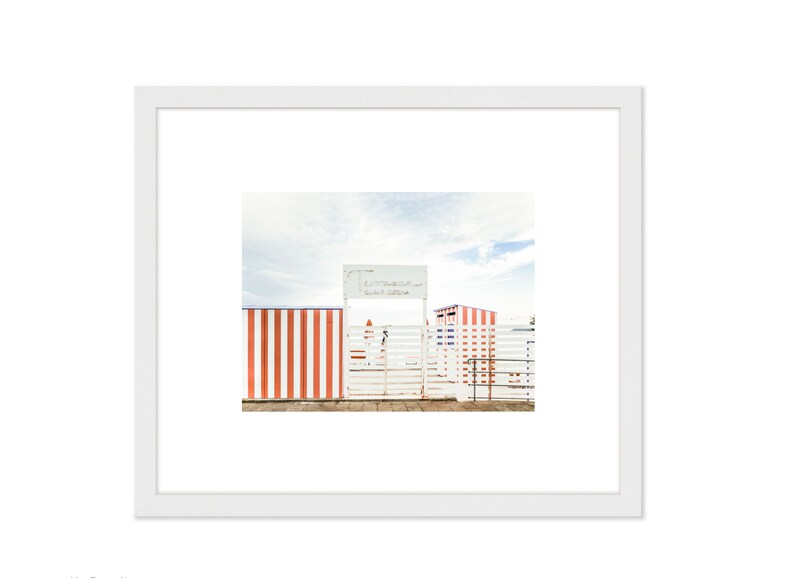 May include: A white gate with a red and white striped fence on either side. The gate has a sign above it that reads "Testaccio Beach Club".