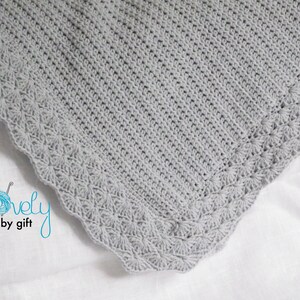 May include: A gray crocheted baby blanket with a delicate scalloped edge.