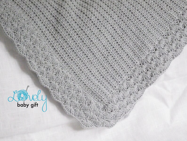 May include: A gray crocheted baby blanket with a delicate scalloped edge.
