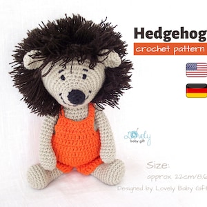Könnte beinhalten: Häkelanleitung für ein Amigurumi-Spielzeug Igel. Der Igel trägt eine orange Latzhose und ist etwa 22 cm groß. Die Anleitung ist in Englisch und Deutsch verfügbar.