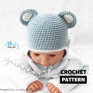 Könnte beinhalten: Eine blaue gehäkelte Baby-Mütze mit weißen Bärenohren und einem weißen gehäkelten Rand. Die Mütze sitzt auf einer Babypuppe, die ein weißes Outfit trägt. Der Text "CROCHET PATTERN" ist auf dem Bild.