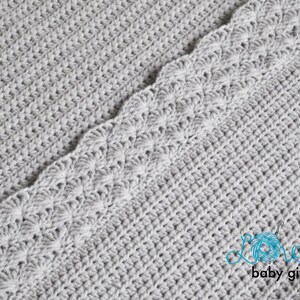 May include: A gray crocheted baby blanket with a scalloped edge. The blanket is made with a simple stitch pattern and has a soft, cozy texture.