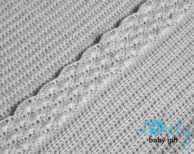 May include: A gray crocheted baby blanket with a scalloped edge. The blanket is made with a simple stitch pattern and has a soft, cozy texture.