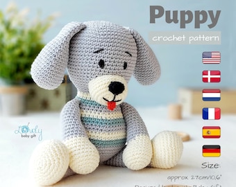 May include: Crocheted puppy toy in gray, white, and blue. The puppy has floppy ears, a black nose, and a red tongue. The text "Puppy crochet pattern" is displayed. The size is approximately 10.6 inches.