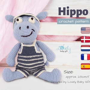 May include: A crocheted blue hippopotamus wearing a white and blue striped outfit and a white hat. The hippopotamus is sitting on a wooden surface. The text "Hippo crochet pattern" is written above the hippopotamus. The text "Size: approx. 28cm/11" is written below the hippopotamus. The text "Designed by Lovely Baby Gift" is written below the size text.