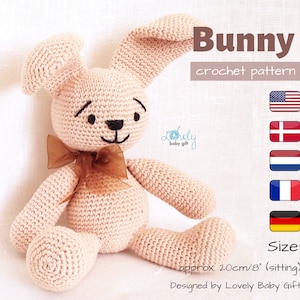 May include: A crocheted pink bunny rabbit sitting with a brown ribbon around its neck. The bunny is approximately 8 inches tall. The image includes the text "Bunny crochet pattern" and "Size: approx 20cm/8" (sitting) Designed by Lovely Baby Gift".