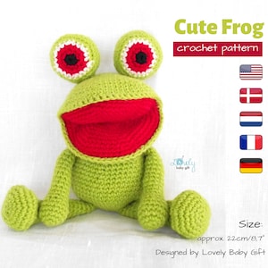 Könnte beinhalten: Ein grünes Häkel-Froschspielzeug mit roten Augen und einem roten Mund. Der Frosch sitzt auf einer weißen Oberfläche. Das Spielzeug ist etwa 22 cm groß. Häkelmuster Niedlicher Frosch.