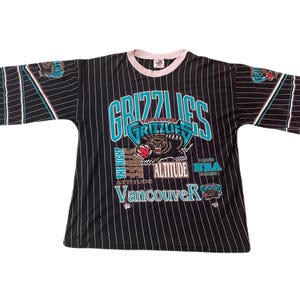 May include: Black and white striped jersey with the text "GRIZZLIES" in teal and white. The jersey features a bear graphic and the words "Vancouver" and "Altitude". The sleeves have teal and white accents.