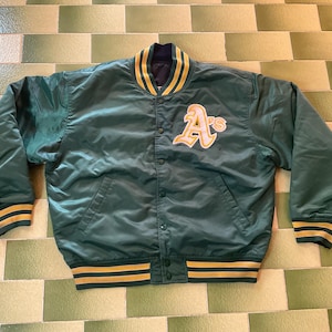 May include: Green satin baseball jacket with gold and white detailing. It has a button-up front, side pockets, and a ribbed collar, cuffs, and hem. The jacket features the letter "A" patch on the chest.