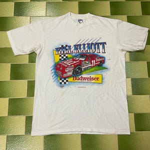 May include: A white ceramic mug with a black handle and the text "But first, coffee" in a black, handwritten-style font. The mug is on a white surface.