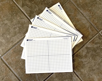 May include: A stack of white rectangular plastic sheets featuring a black printed centimeter grid with an X-Y axis. Each sheet is enclosed in a clear protective sleeve and displays the Classroom Products logo and the text Centimeter Grid X-Y Axis.