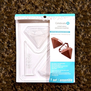 May include: A clear plastic 3-part mold for making diamond-shaped treats. The package includes a picture of the finished product, a brown diamond-shaped treat filled with white candies. The package reads "Celebrate it" and "3-PART MOLD".