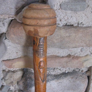 May include: A wooden walking stick with a carved top and intricate designs. The stick is brown and has a natural finish.