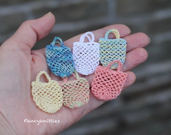 May include: Six small crocheted mesh bags in various colors, including blue, white, yellow, pink, and green. The bags are displayed in a hand, with the text "Fancyknittles" visible at the bottom of the image.