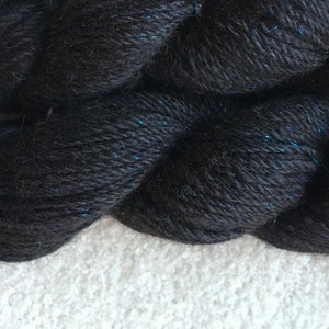 May include: Black yarn with a subtle blue sparkle. The yarn is soft and fluffy, and it is perfect for knitting or crocheting.