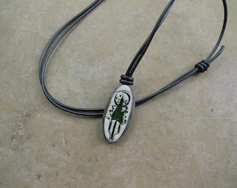 May include: A black leather cord necklace with an oval pendant featuring a green tree design.