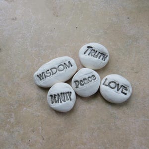 May include: Six white stones with the words "Wisdom", "Truth", "Peace", "Love", "Beauty" inscribed on them.
