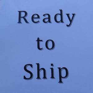 May include: Text on a light blue background reads "Ready to Ship" in a dark, serif font. The words are centered and stacked vertically, with "to" in a smaller font size.