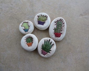 May include: Six white ceramic coasters with different green and brown cactus designs. Each coaster features a cactus in a pot.