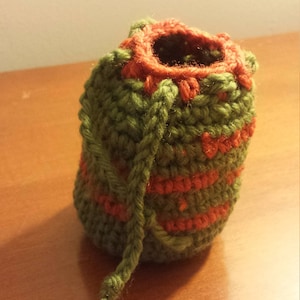 May include: A small green and orange crocheted drawstring pouch with a long green cord.