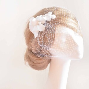 May include: White bridal veil with a white flower embellishment.