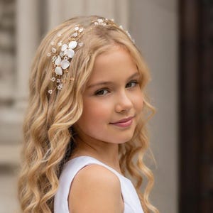 May include: A gold-toned hair vine featuring white floral accents and small clear crystals. The accessory is designed with thin, flexible wire branches that hold the delicate flowers and sparkling stones in place, creating a decorative piece for hair.