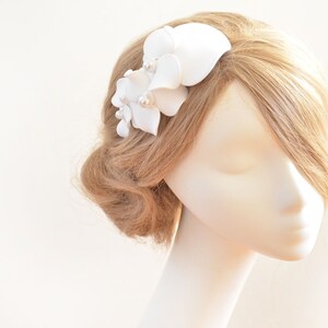 May include: White flower hair comb with pearl accents. The comb is made of fabric and is designed to be worn in the hair.