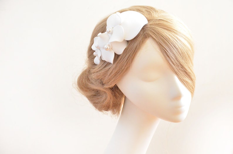 May include: White flower hair comb with pearl accents. The comb is made of fabric and is designed to be worn in the hair.