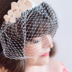 May include: A white bridal veil with a delicate floral design. The veil is made of soft tulle and features a row of white flowers.