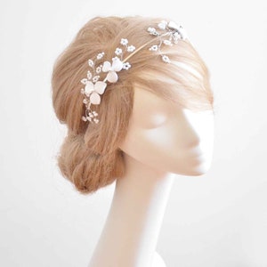 May include: A gold-toned metal headband featuring delicate wire branches adorned with small white floral accents and tiny pearl-like beads. The flexible wire structure allows for intricate positioning across the hair, showcasing a botanical design.