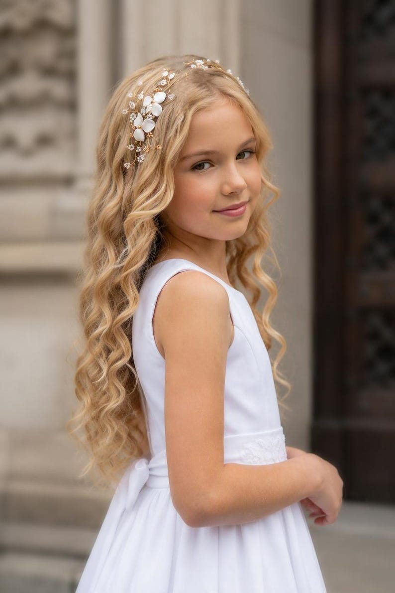 May include: A gold-toned hair vine featuring white floral accents and small clear crystals. The accessory is designed with thin, flexible wire branches that hold the delicate flowers and sparkling stones in place, creating a decorative piece for hair.