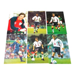 May include: A set of six football trading cards featuring English players. The cards show players in action on a green pitch, wearing their team's kit. The cards are rectangular and have a glossy finish.