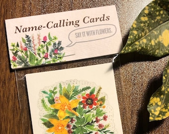 May include: A set of greeting cards with a watercolor illustration of a bouquet of yellow and red flowers with green leaves. The text on the card reads "Name-Calling Cards Say It With Flowers."