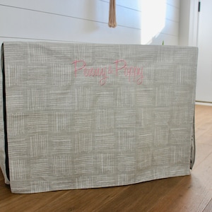 May include: A gray and white patterned dog crate cover with the text "Penny & Poppy" embroidered in pink.
