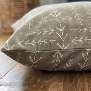 May include: A grey and white patterned dog bed with a white background and a grey pattern of small branches.