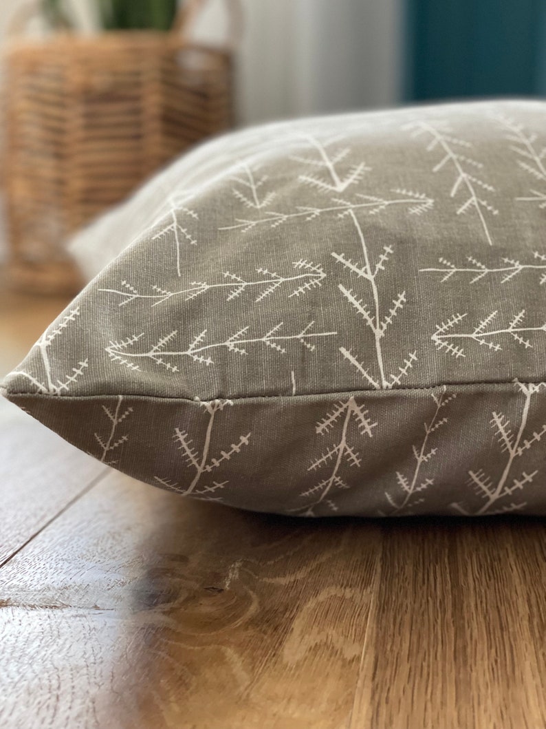 May include: A grey and white patterned dog bed with a white background and a grey pattern of small branches.