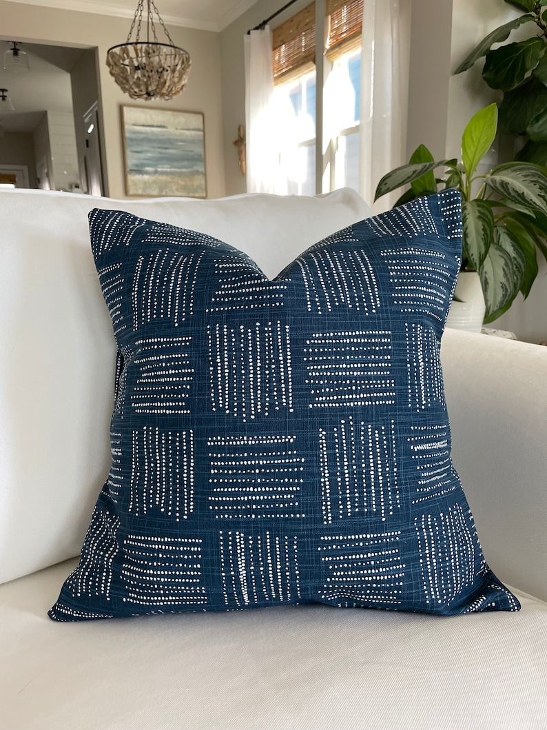 Peut inclure: Un coussin de canap&eacute; bleu marine avec un motif g&eacute;om&eacute;trique blanc. Le motif est compos&eacute; de petits points blancs dispos&eacute;s en carr&eacute;s et en lignes.