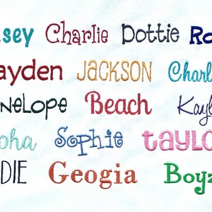 May include: A white fabric background with embroidered names in various colours, including Casey, Charlie, Dottie, Ross, Hayden, JACKSON, Charlotte, Penelope, Beach, Kaylee, Aloha, Sophie, taylor, SADIE, Geogia, and Boyz.