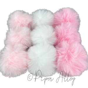 May include: A collection of fluffy pom poms in pink and white. The pom poms are arranged in a circle, with the pink pom poms on the outside and the white pom poms in the center.