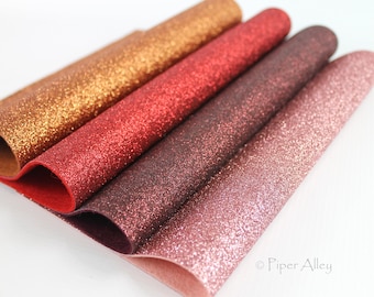 May include: Four rolls of glitter fabric in shades of gold, red, burgundy, and pink. The fabric is textured with glitter.