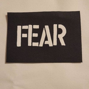 May include: Black fabric patch with the word "FEAR" printed in white.