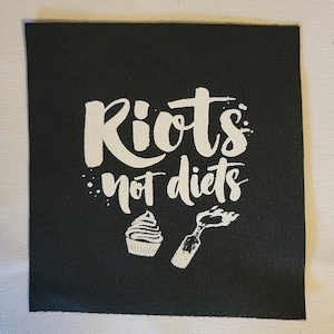 May include: Black fabric patch with white text that reads "Riots not diets" with a cupcake and a lit Molotov cocktail graphic.