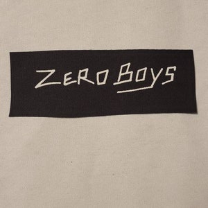 May include: Black fabric patch with white text that reads "ZERO BOYS".