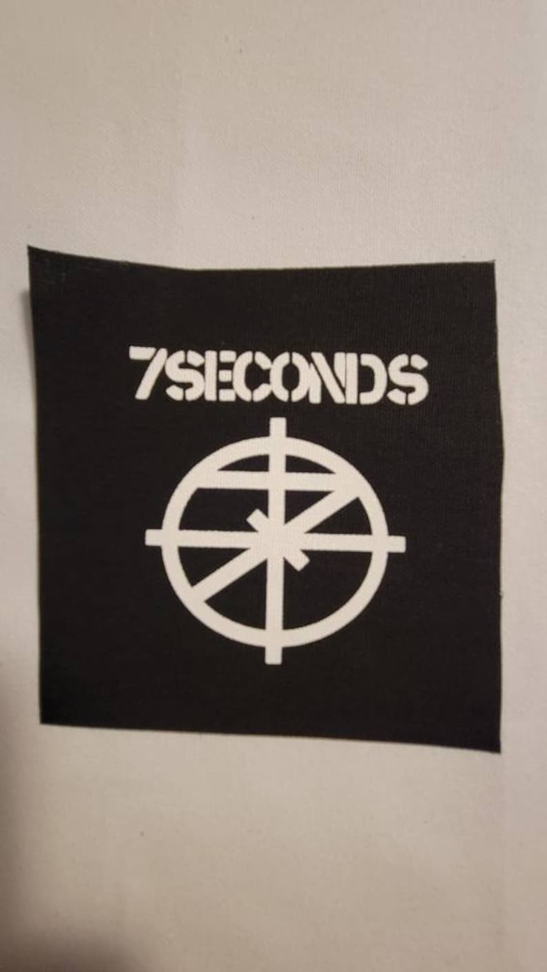 May include: Black and white patch with the text "7 Seconds" and a circle with a cross inside.