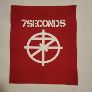 May include: Red fabric patch with white text that reads "7 SECONDS" and a white circle with a cross inside.